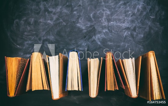 Picture of Vintage books standing on blackboard background - top view